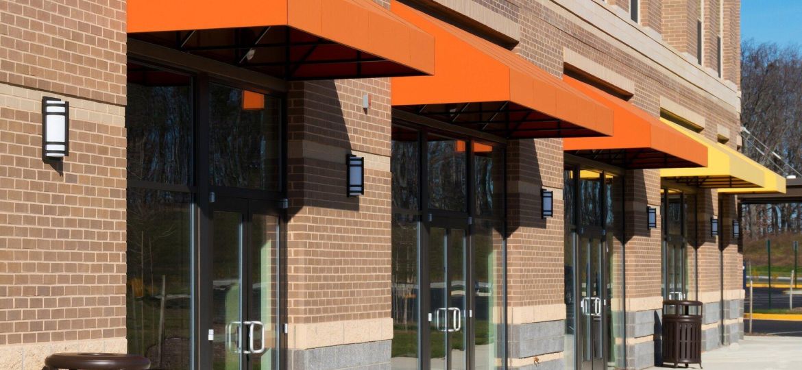 Outside of a commercial building with 3 orange awnings and 1 yellow to represent commercial property insurance coverage.