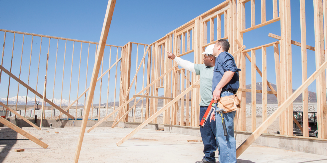 two construction workers framing building on cement
